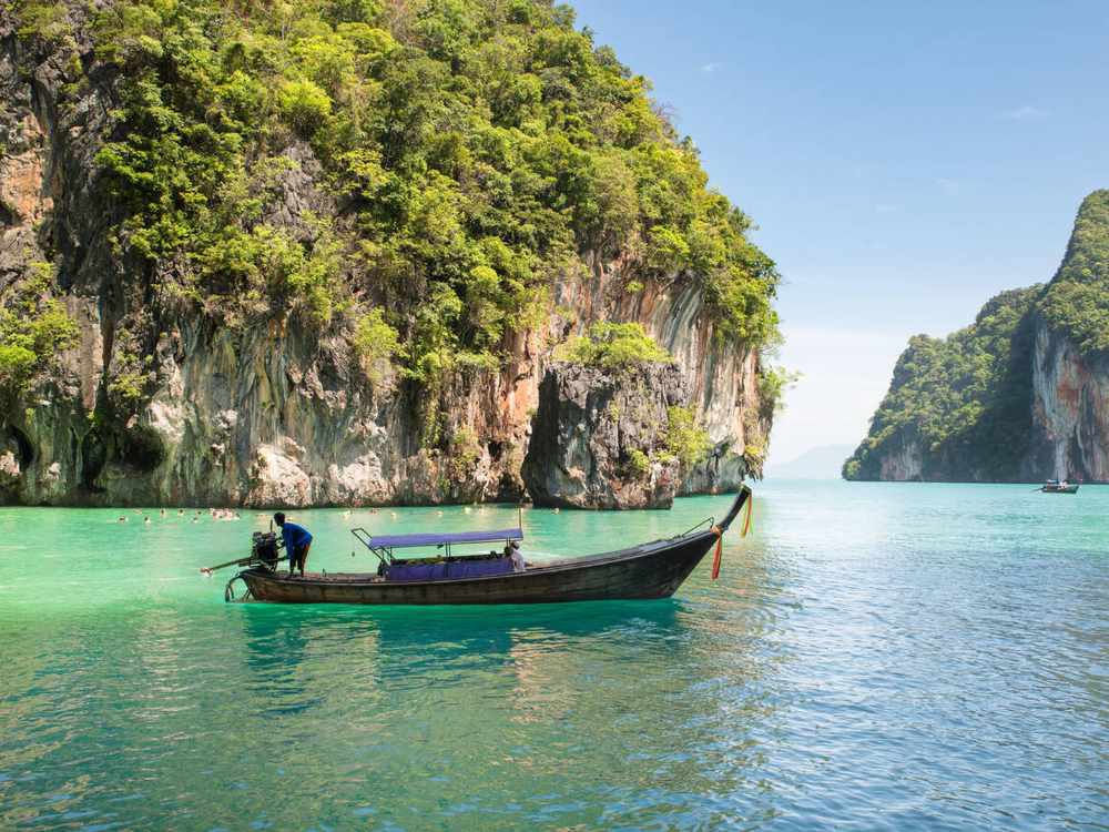 Beautiful landscape of rocks mountain and crystal clear sea with longtail boat at Phuket, Thailand.