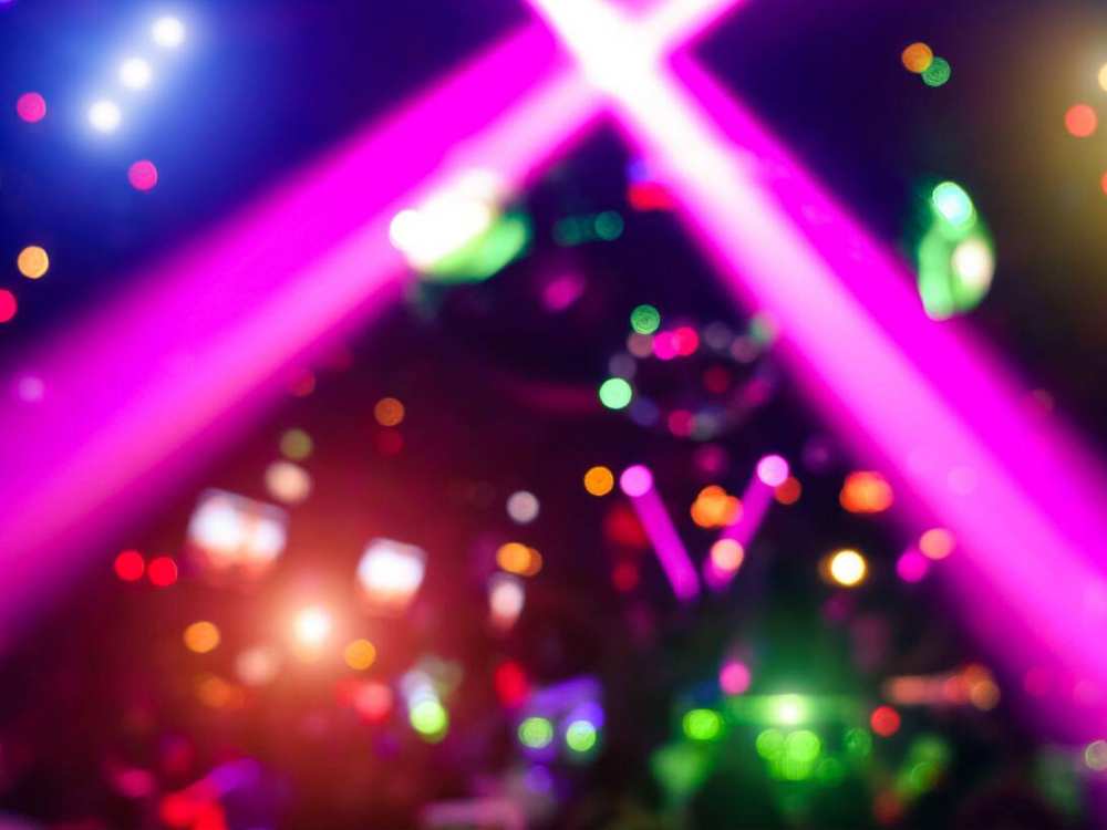 Laser show inside a nightclub with colorful beams cutting through the dark crowded room