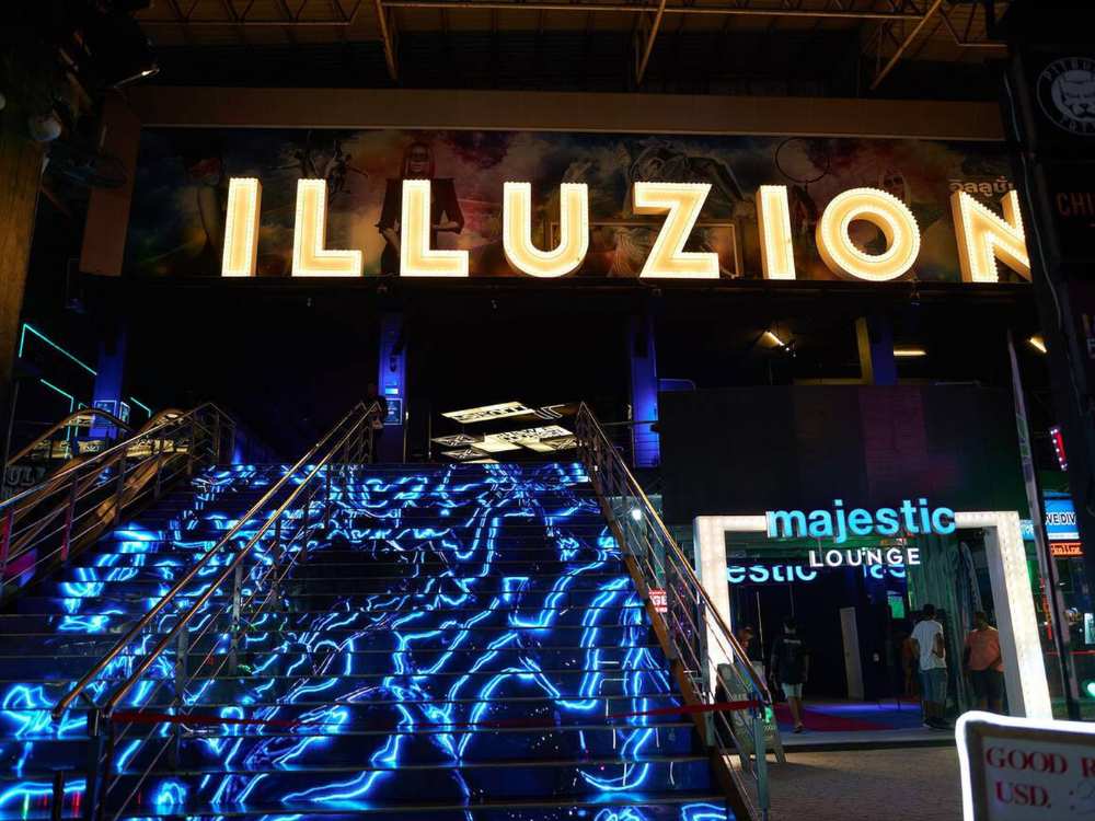 Entrance of Illuzion Nightclub in Phuket with vibrant neon lights, a crowded walkway, and a lively nightlife atmosphere.