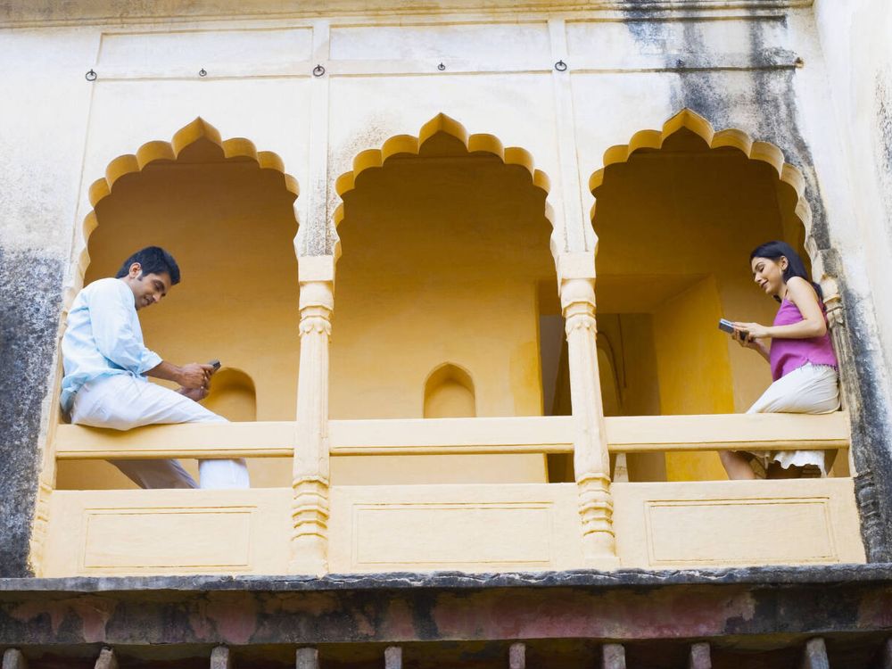 young couple sitting on a railing, Neemrana Fort Palace