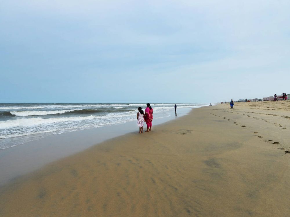 A mother and her daughter are standing by Marina Beach in Chennai.