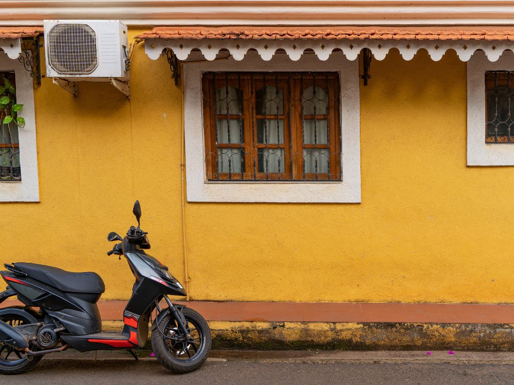 A yellow Portuguese-style heritage house with a scooter parked outside in Fontainhas, Goa.