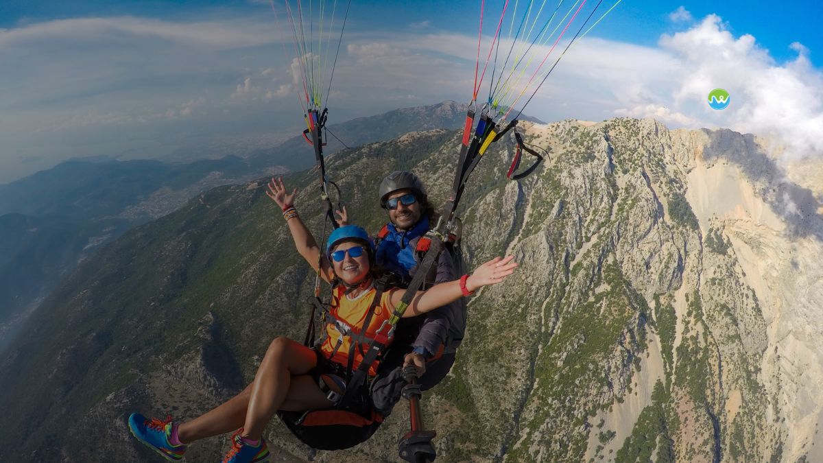 2 people paragliding together and smiling at the photo